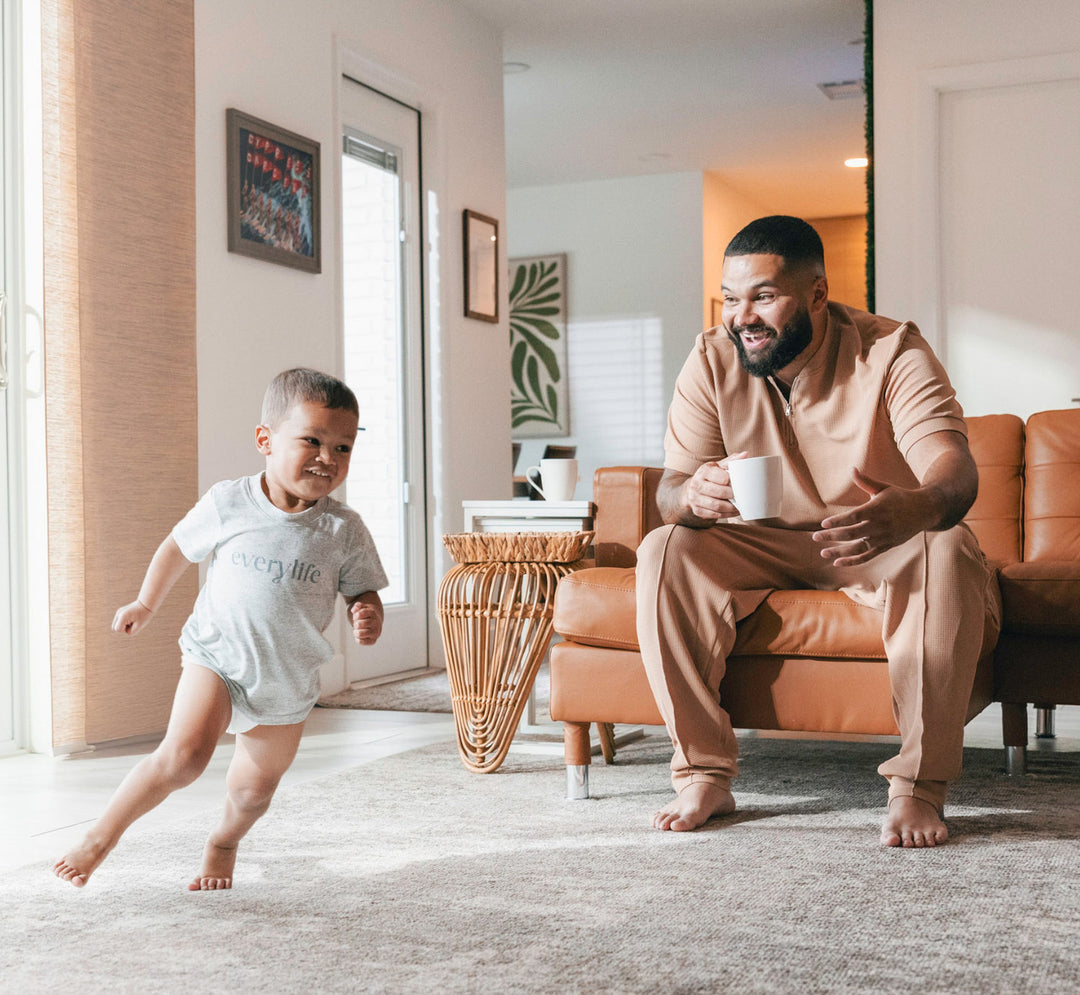 father watching son in training pants run through the living room